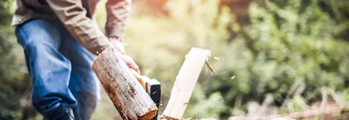 Person hackt mit Axt Holz